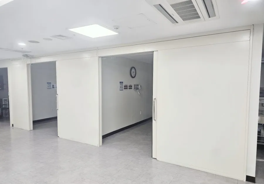 병원 홀에 설치된 폭 7,500mm 일체형 대형 미닫이문이 일부 열려 있는 모습